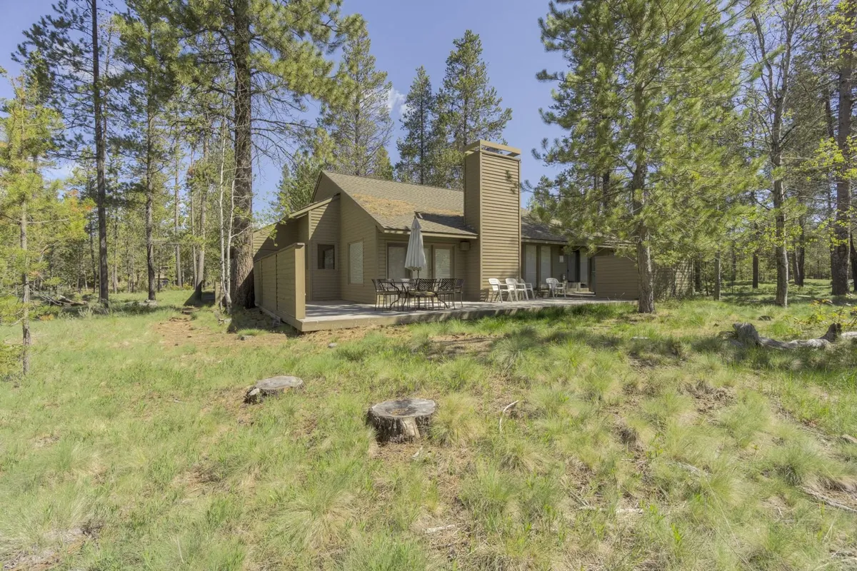A view of the home’s deck nestled among tall trees, with outdoor seating inviting families to gather, dine, or simply relax. The tranquil setting highlights the connection between indoor and outdoor living.