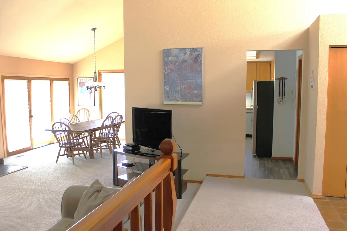 This image captures a spacious open-plan dining area with a large table perfect for group meals, a television for entertainment, and a view into the kitchen. The space is well-lit and features inviting decor, setting the scene for social activities and shared moments.
