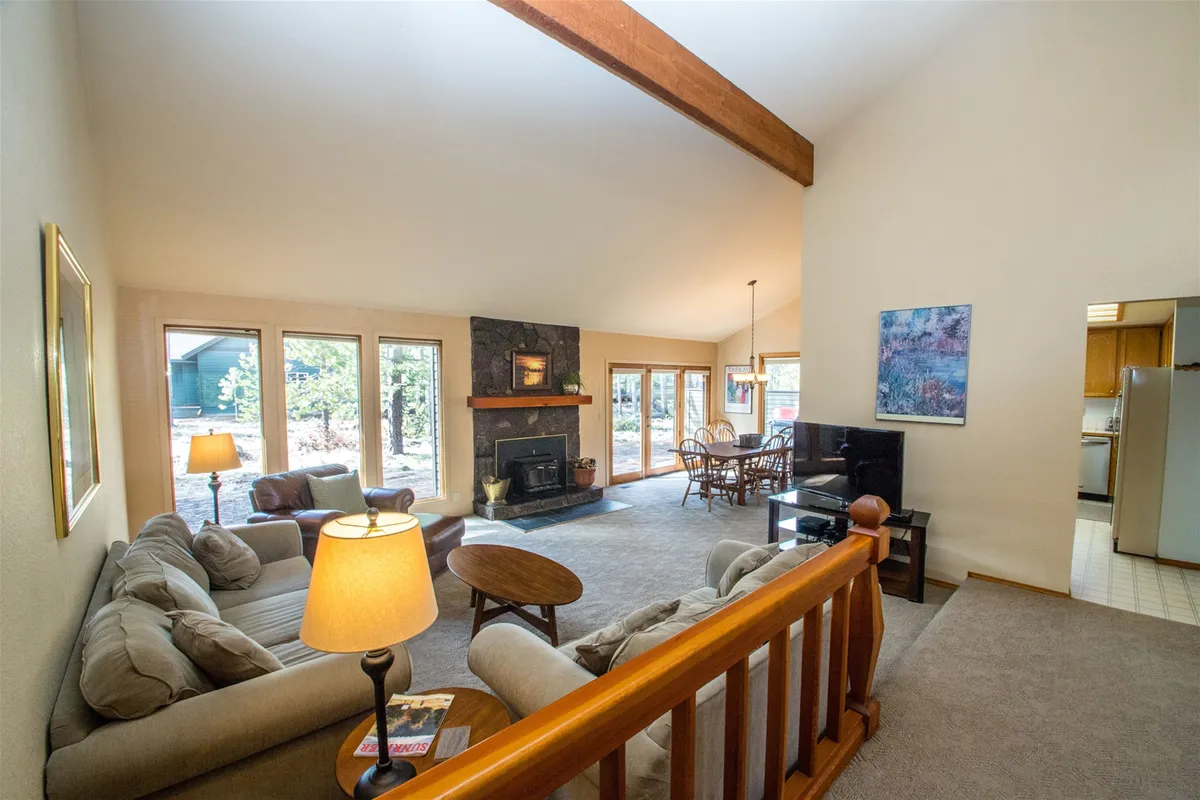 The hero image showcases a spacious, light-filled living area with a cozy fireplace, large windows inviting in natural light, plush seating perfect for gathering, and a stylish dining area—all set in an open-concept layout that feels both inviting and modern.