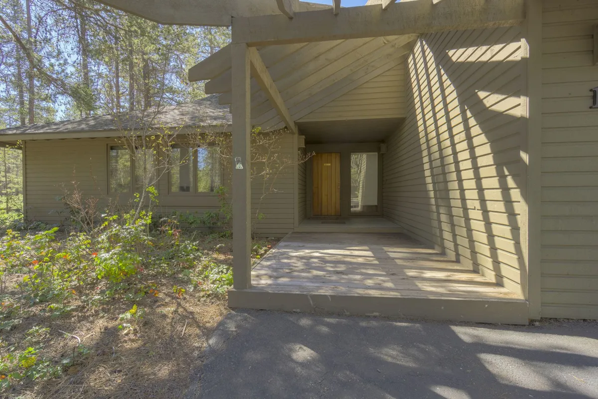 This image features the home’s entrance porch framed by inviting wooden front doors, surrounded by lush trees. The setting is welcoming, blending the natural Sunriver landscape with the promise of comfortable accommodations.