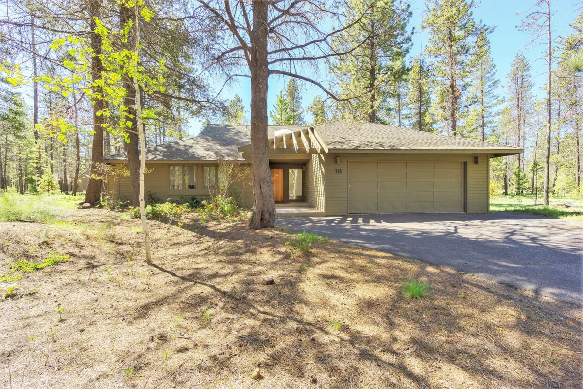 The home’s front exterior, showcasing the front porch, visible garage, and lush surrounding trees. The garage is prominent, suggesting ample space for storing adventure gear and bikes, while the porch invites outdoor relaxation.