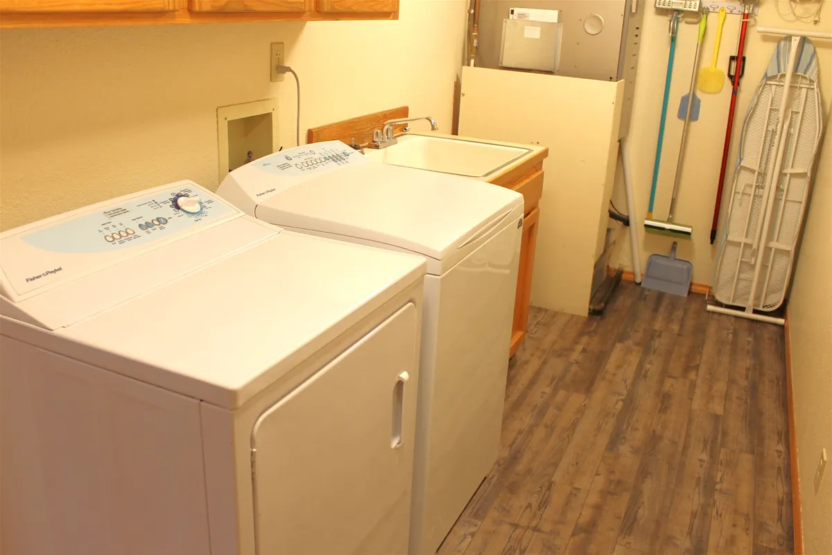 A tidy utility room with a washing machine, dryer, and utility sink, designed for practical use. The space is organized, emphasizing convenience for managing gear and post-adventure clothing.