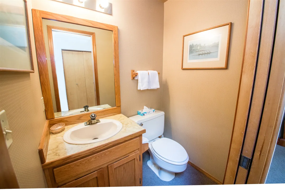 A calm and practical bathroom featuring a vanity with sink, a mirror, toilet, and framed artwork. The space feels tranquil, ideal for personal grooming and relaxation at the start or end of the day.