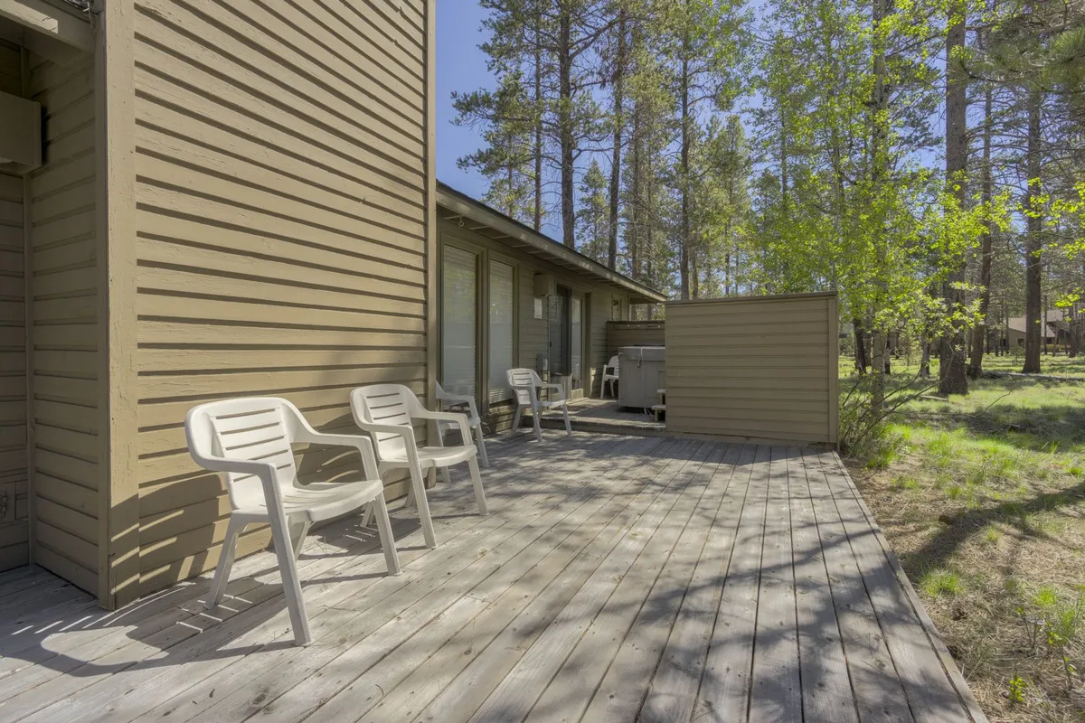 An inviting outdoor deck surrounded by tall trees, featuring comfortable chairs perfect for relaxing or socializing. The space is peaceful, offering views of the natural landscape and a serene connection to the outdoors.